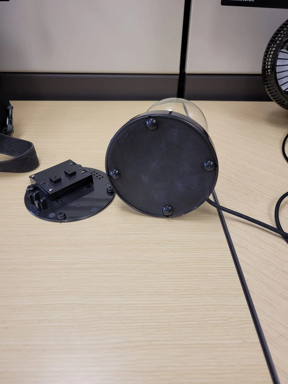 The 3D-printed replacement base with rubber feet, beside the original battery cover it replaced