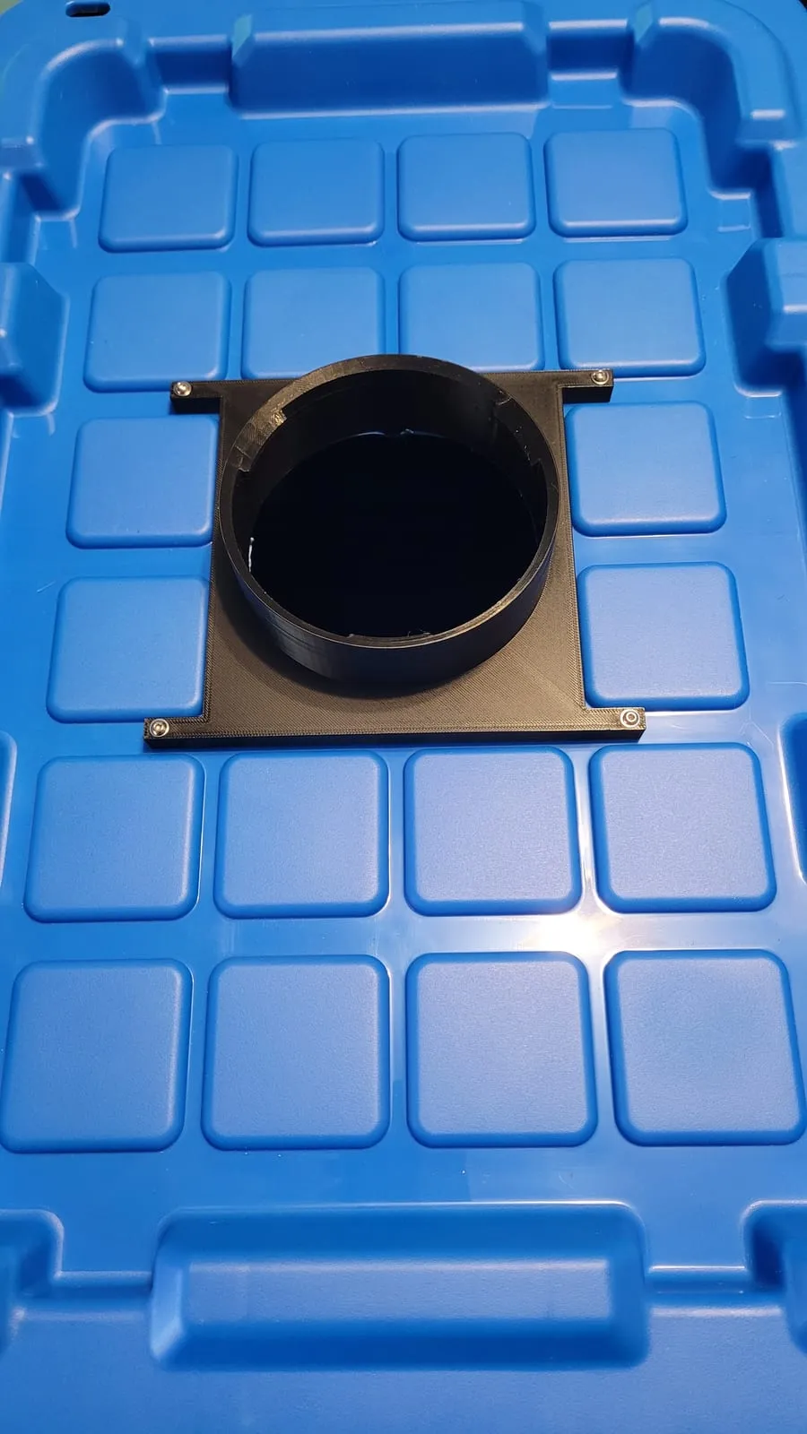 A black 3D-printed mounting flange bolted to a blue reservoir lid