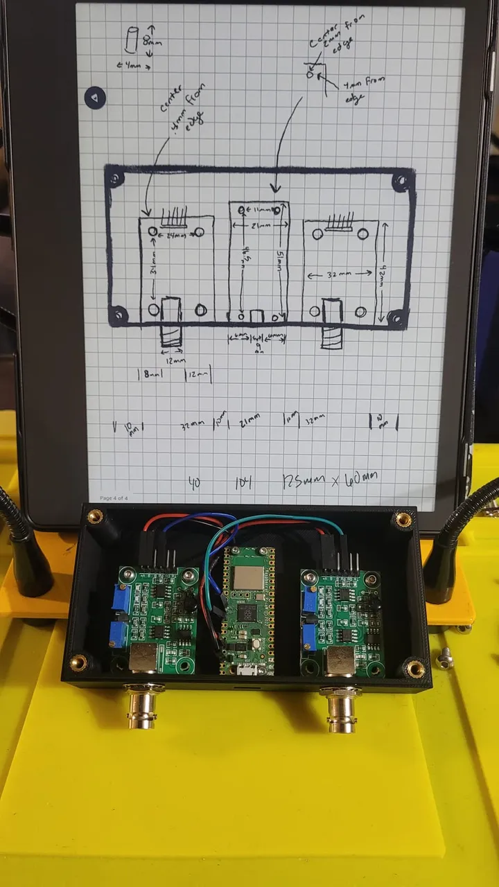 A 3D-printed enclosure holding a Raspberry Pi Pico and sensor boards, beside the hand-drawn design sketch
