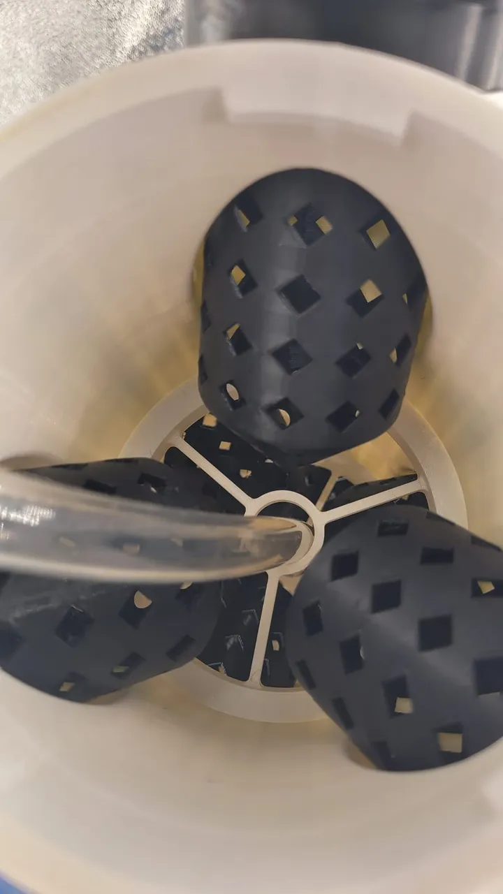 Black 3D-printed mesh grow pods seated in the white printed tower body