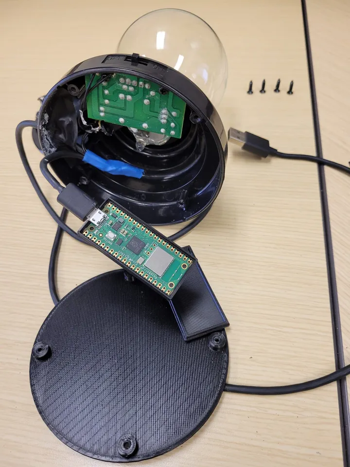 A plasma globe opened at the base, exposing the driver board and a Raspberry Pi Pico W wired to USB