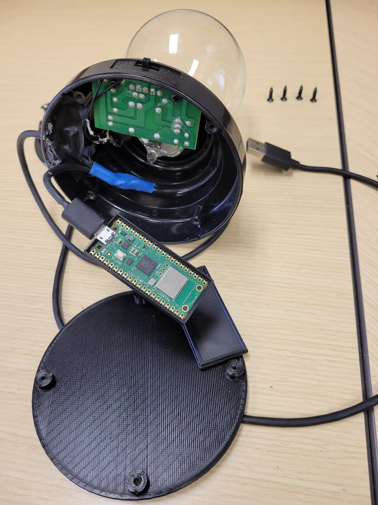 A plasma globe opened at the base, exposing the driver board and a Raspberry Pi Pico W wired to USB