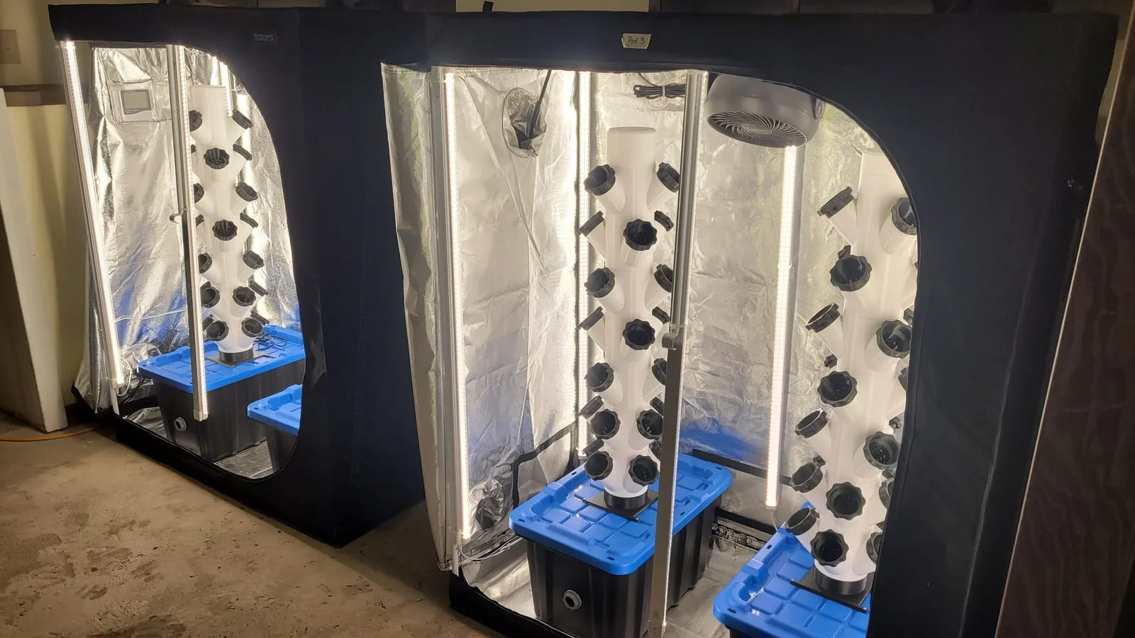 White 3D-printed towers in reflective grow tents, each on a blue reservoir under an LED bar